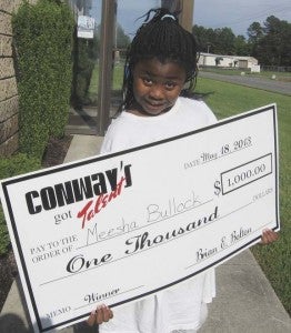 Mesha Bullock, 9, of Franklin, holds up a $1,000 check (name misspelled on check) she won during the Conway’s Got Talent contest. -- Stephen H. Cowles | Tidewater News