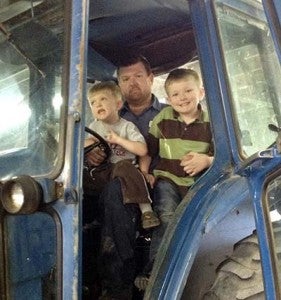 George Collins Jr. with his sons Camden, left, and Dawson in the cab of a farm tractor. Dawson is the one who will likely become an auto mechanic like his father and grandfather. -- SUBMITTED