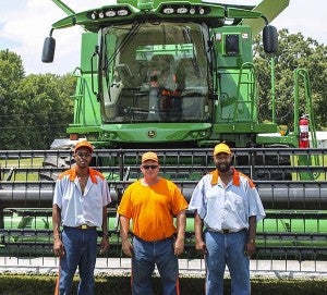 Three offenders at the Deerfield Men’s Work Center in front of John Deere farm combine used at the correctional center. -- SUBMITTED