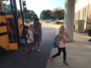 Assistant headmaster Faith Best greets returning students as they get off the bus.